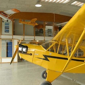 Í forgrunni á þessari mynd sést Piper J-3 Cub TF-CUB en úr loftinu hanga flugmódel af Bellanca Citabria og Piper Cub. Ennfremur sést hér sýningarsalurinn sem var á efri hæð gamla flugsafnsins.