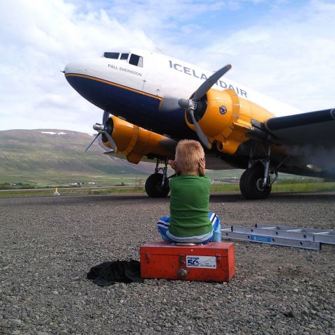 Sá stutti heldur fyrir eyrun. Hann situr á verkfærakassa með merki Fokker-50 og horfir á gamla Þristinn fara í gang.